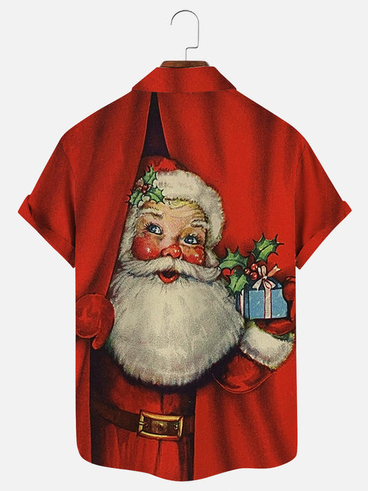 Santa Claus behind curtain holding small gift graphic printed holiday short sleeve shirt